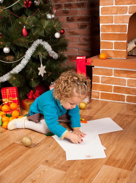 Little girl drawing near Christmas tree — Stock Photo, Image