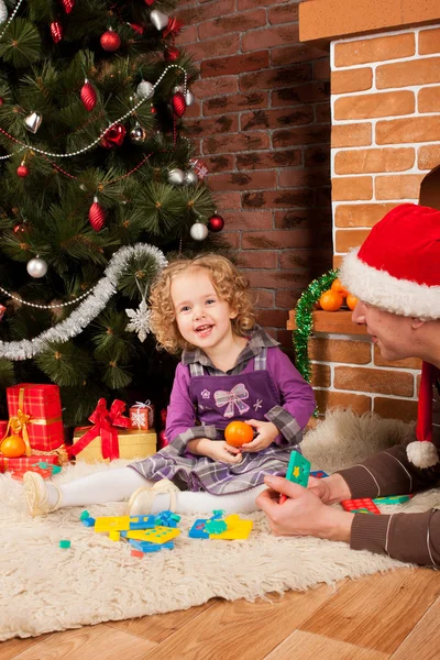 Little girl play with dad near Christmas tree — Stock Photo, Image