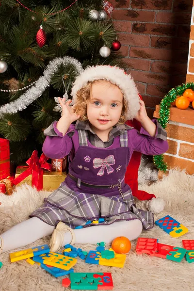 Kleines Mädchen spielt in der Nähe des Weihnachtsbaums — Stockfoto