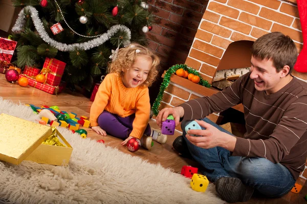 Kleines Mädchen spielt mit Papa in der Nähe des Weihnachtsbaums — Stockfoto