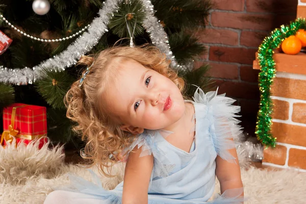 クリスマスの木の近くに座っている小さな女の子 — ストック写真