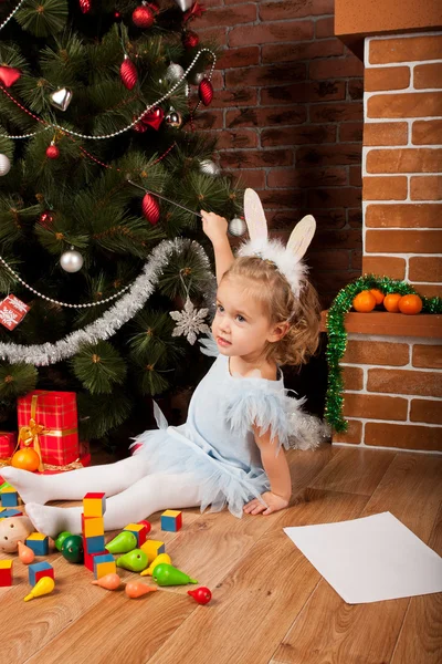 Menina sentada perto da árvore de Natal — Fotografia de Stock