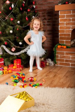 Little girl staying near Christmas tree clipart