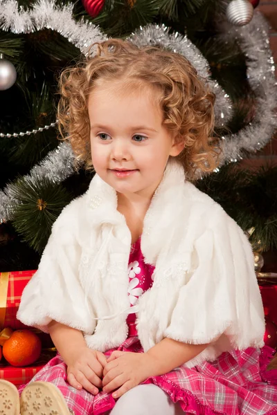 Menina sentada perto da árvore de Natal — Fotografia de Stock