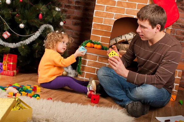 Liten flicka spelar med pappa nära julgran — Stockfoto
