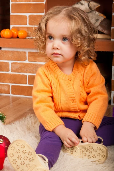 Kleines Mädchen sitzt in der Nähe von Kamin — Stockfoto