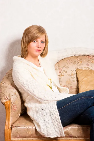 Ung kvinna sitter på en soffa — Stockfoto