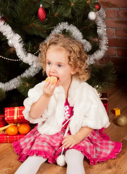 Хищная маленькая девочка ест мандарин — стоковое фото
