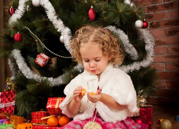 Хищная маленькая девочка ест мандарин — стоковое фото