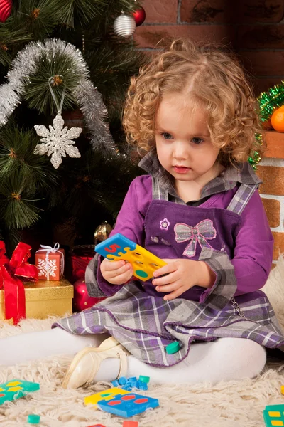Kleines Mädchen spielt in der Nähe des Weihnachtsbaums — Stockfoto