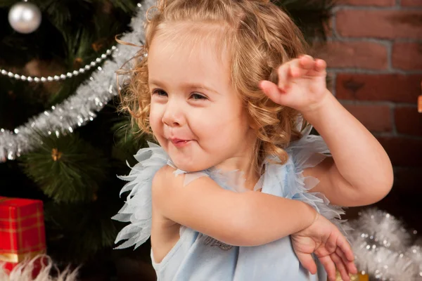 Маленькая девочка сидит возле рождественской елки — стоковое фото