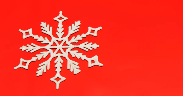 Die große Schneeflocke auf rotem Hintergrund — Stockfoto