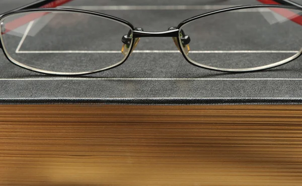 Bril op het oude dikke boek — Stockfoto