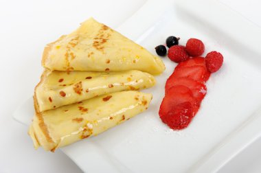 Crepe on a plate with a strawberry, a raspberry and a bilberry clipart