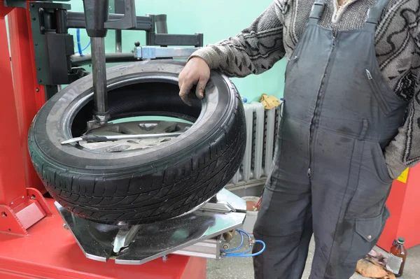 Il meccanico di auto cambia una copertura di pneumatico su una ruota di automobile — Foto Stock