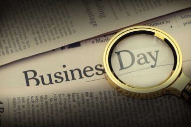 Loupe lies on the newspaper with title Business day.Selective li clipart