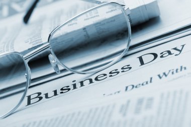 Eyeglasses lie on the newspaper with title Business day. Blue to clipart