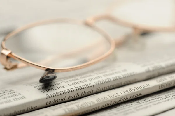 Eyeglasses lie on a pile of newspapers — Stock Photo, Image
