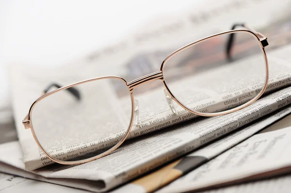 Szemüvegek feküdjön egy halom újságok — Stock Fotó