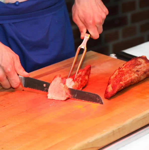 Un cocinero corta carne en el buffet —  Fotos de Stock