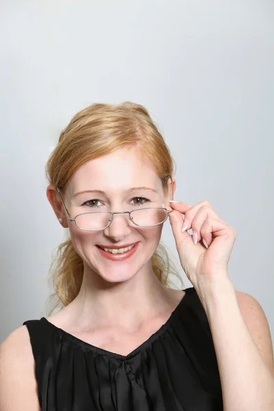 Jovem mulher rindo olha sobre seus óculos — Fotografia de Stock