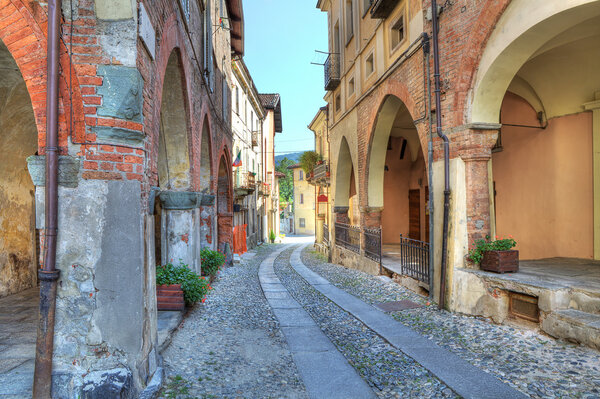 Narrow paved street among vintage brick houses in town of Avigliana, northern Italy.