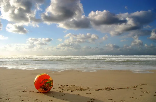 Παιχνίδι μπάλα το καλοκαίρι στην παραλία κάτω από τον θολό ουρανό. — Φωτογραφία Αρχείου