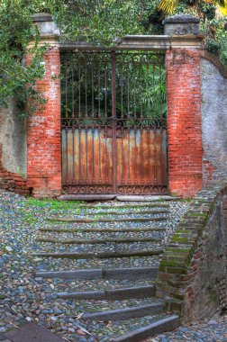 Old rusty gate and paved stairs in Saluzzo. clipart