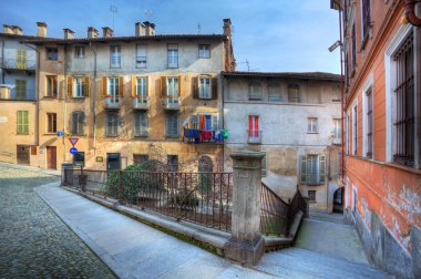 Paved street and old houses in Saluzzo, Italy. clipart