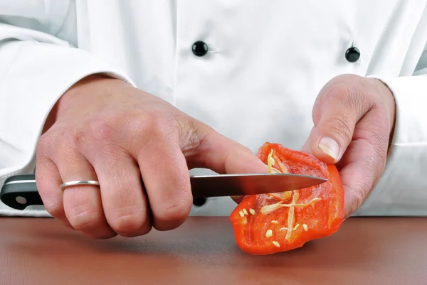 Female chef preparing red paprika with a kitchen knife — Stock Photo, Image