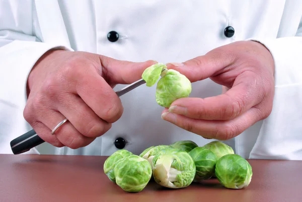 La chef limpia coles de Bruselas con un cuchillo —  Fotos de Stock