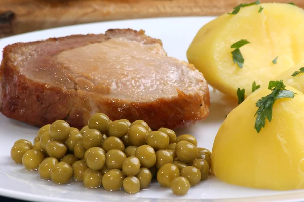 Geroosterd varkensvlees met gekookte aardappels en erwten — Stockfoto