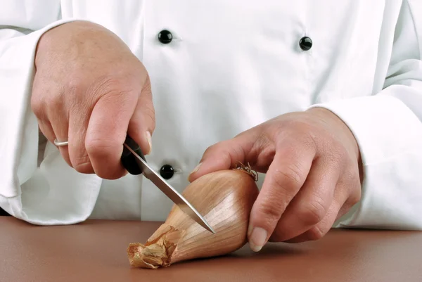 Female chef cut an onion with a kitchen knife — Stock Photo, Image