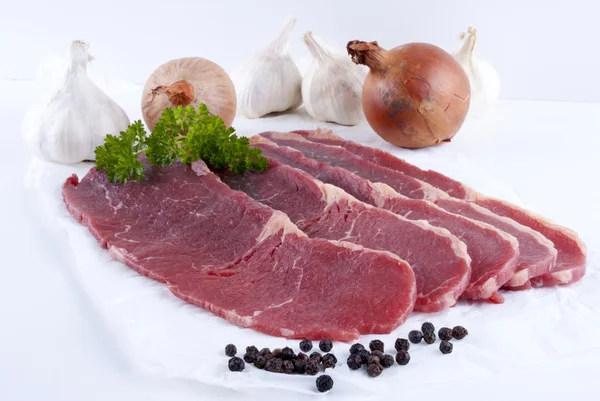 Thin cut beef steaks with garlic and onions — Stock Photo, Image