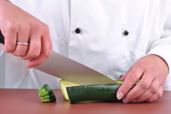 Köchin schneidet eine Zucchini mit einem Küchenmesser — Stockfoto