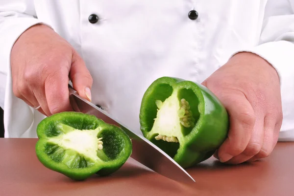 Ženské šéfkuchař připravuje zelené papriky s kuchyňským nožem — Stock fotografie