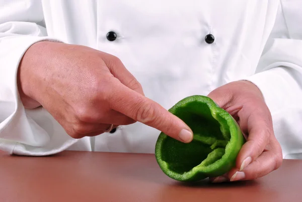 Kobieta kucharz pokazuje z jej palec na zielonym pieprzem — Zdjęcie stockowe