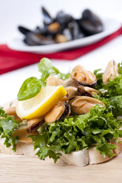Cooked mussels with lemon, fresh salad on toast — Stock Photo, Image