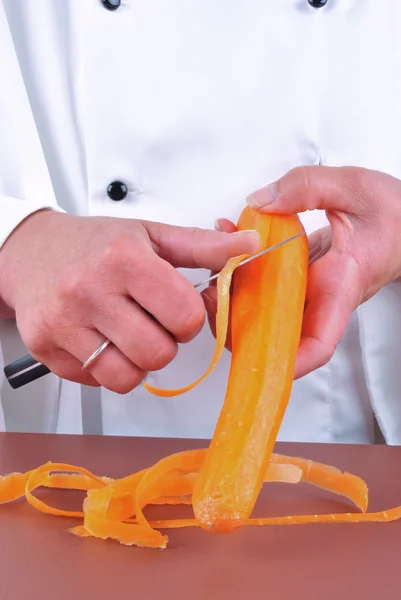 Köchin schneidet mit Küchenmesser eine Möhre — Stockfoto