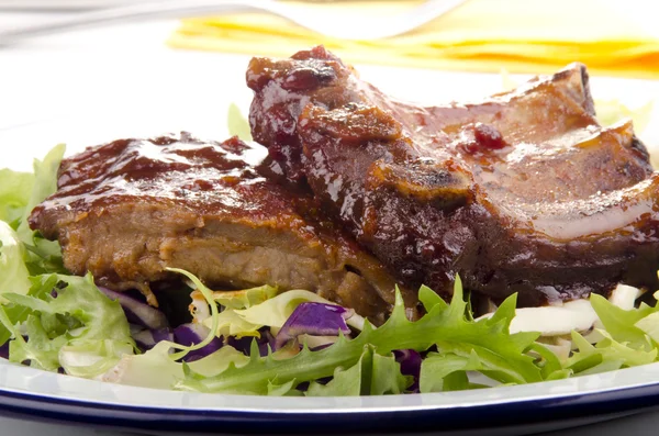 Барбекю запасные ребрышки на тарелке со свежим салатом — стоковое фото