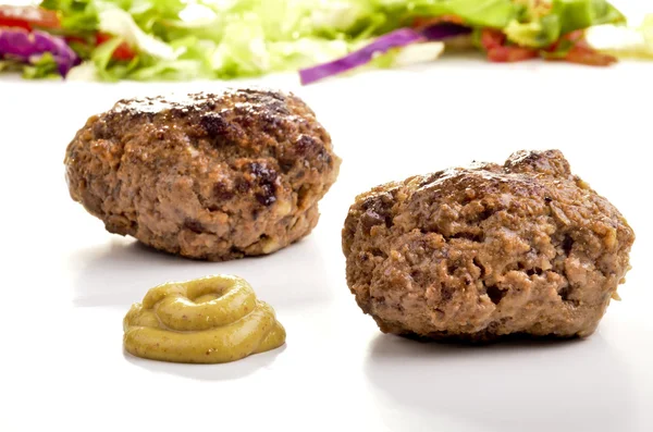 Two freshly grilled meatballs and some mustard — Stock Photo, Image