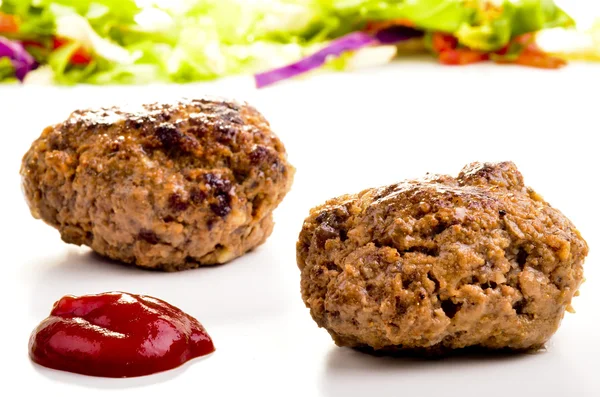 Zelfgemaakte gehaktballen met ketchup en salade in de achtergrond — Stockfoto