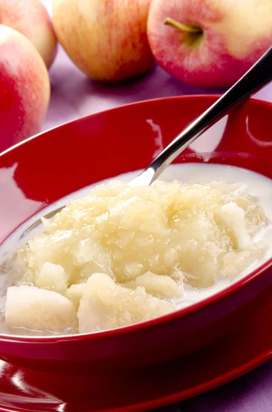 Äppelmos med färsk mjölk i en röd skål — Stockfoto