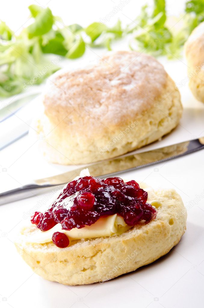Scone spread with butter and cranberry jam