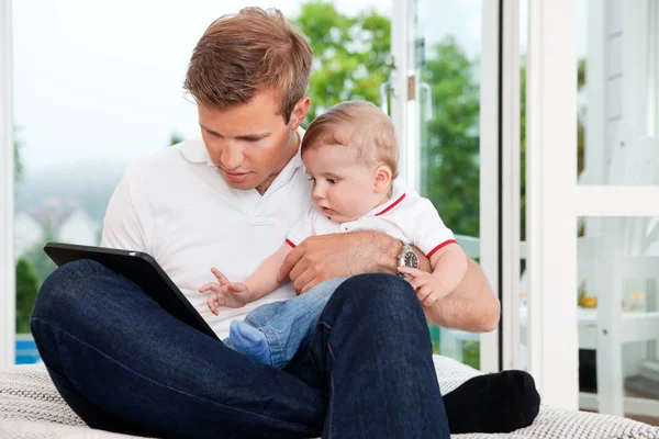 Uomo che utilizza la tavoletta digitale mentre tiene bambino — Foto Stock