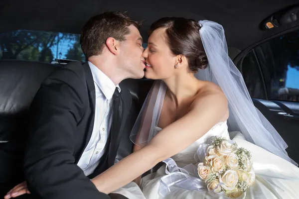 Hochzeitspaar küsst sich in Limousine — Stockfoto