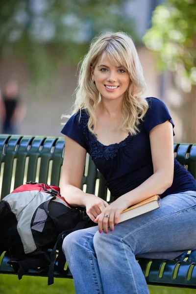 Estudante do sexo feminino sentado no banco — Fotografia de Stock