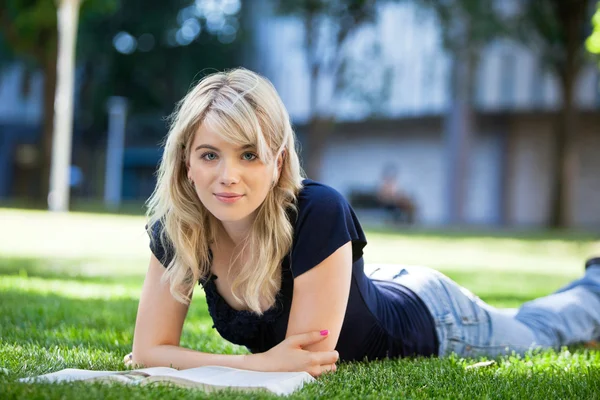 Chica acostada en la hierba con un libro — Foto de Stock