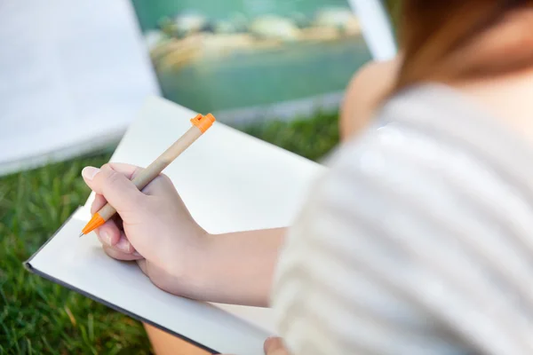 Mädchen schreibt in ein Notizbuch — Stockfoto