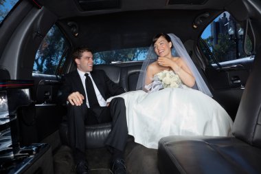 Newly wed couple in limousine clipart